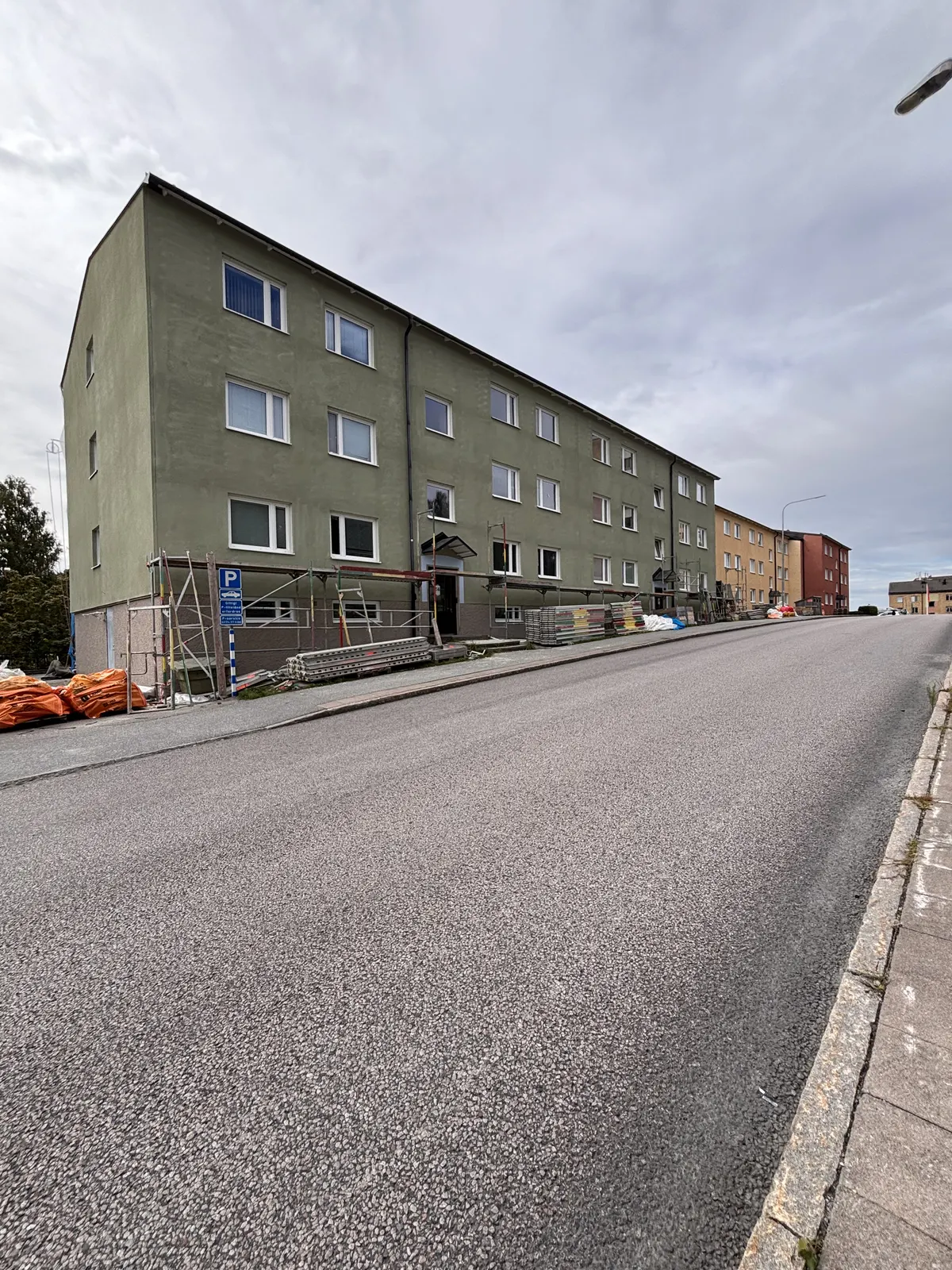 Färdigrenoverat flerbostadshus i grön puts sett från gatan
