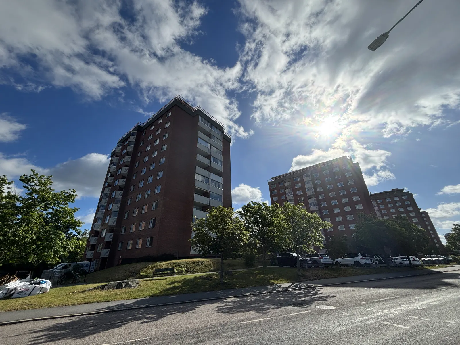 Två flerbostadshus i rött tegel med parkering i förgrunden