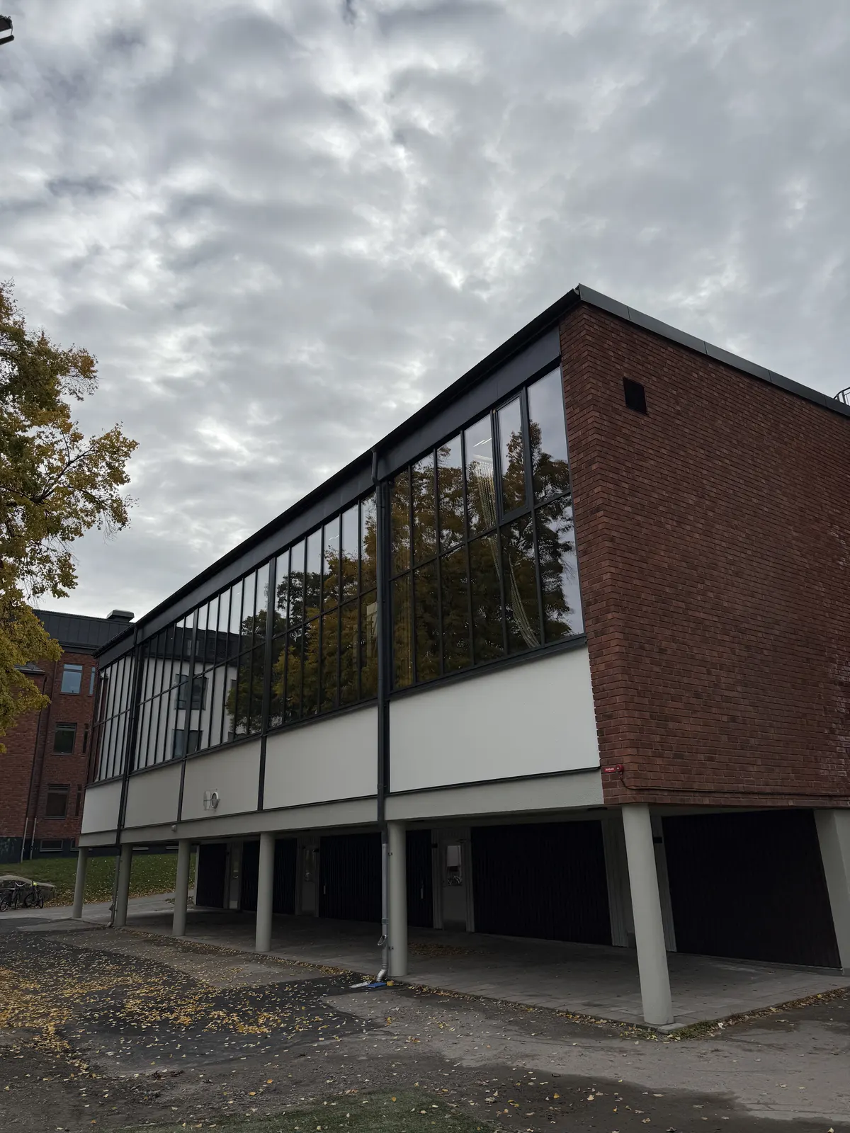 Skolbyggnad i rött tegel med stor glasfasad och pelarburen överbyggnad