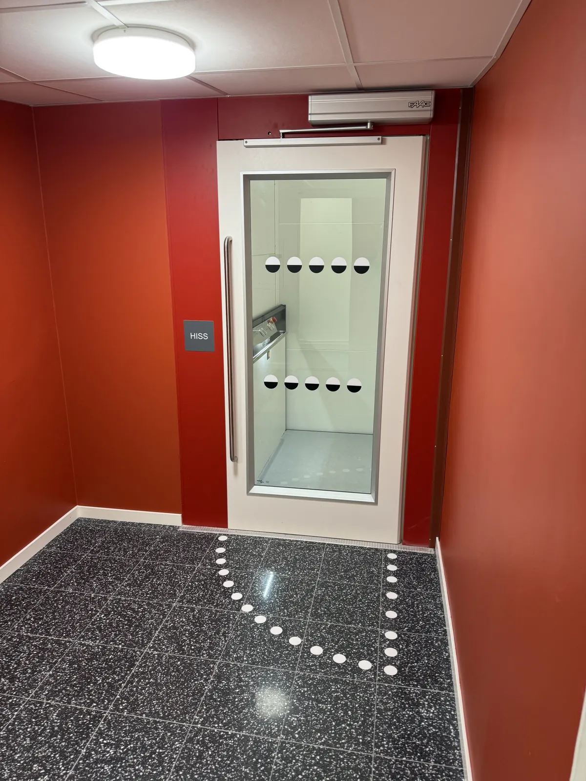 Entré med röd vägg, glasdörr och terrazzogolv