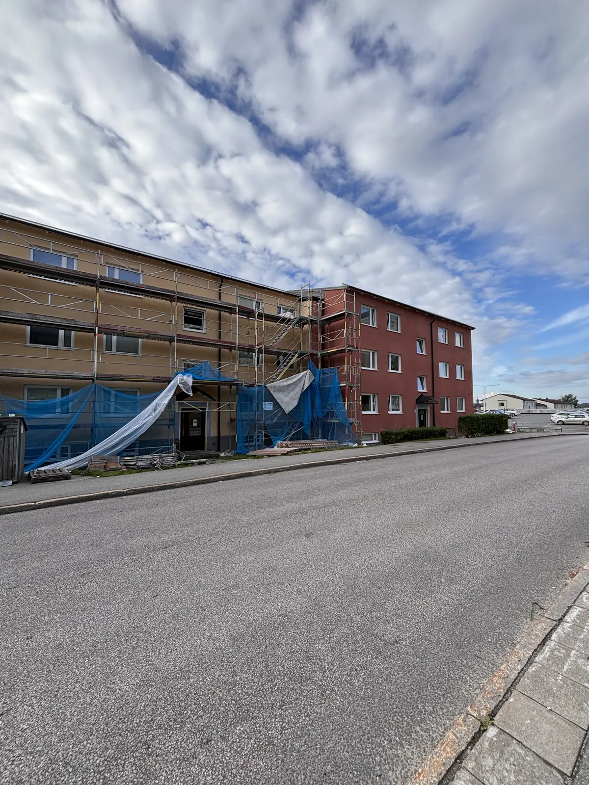 Byggnadslänga under fasadrenovering sedd längs gatan