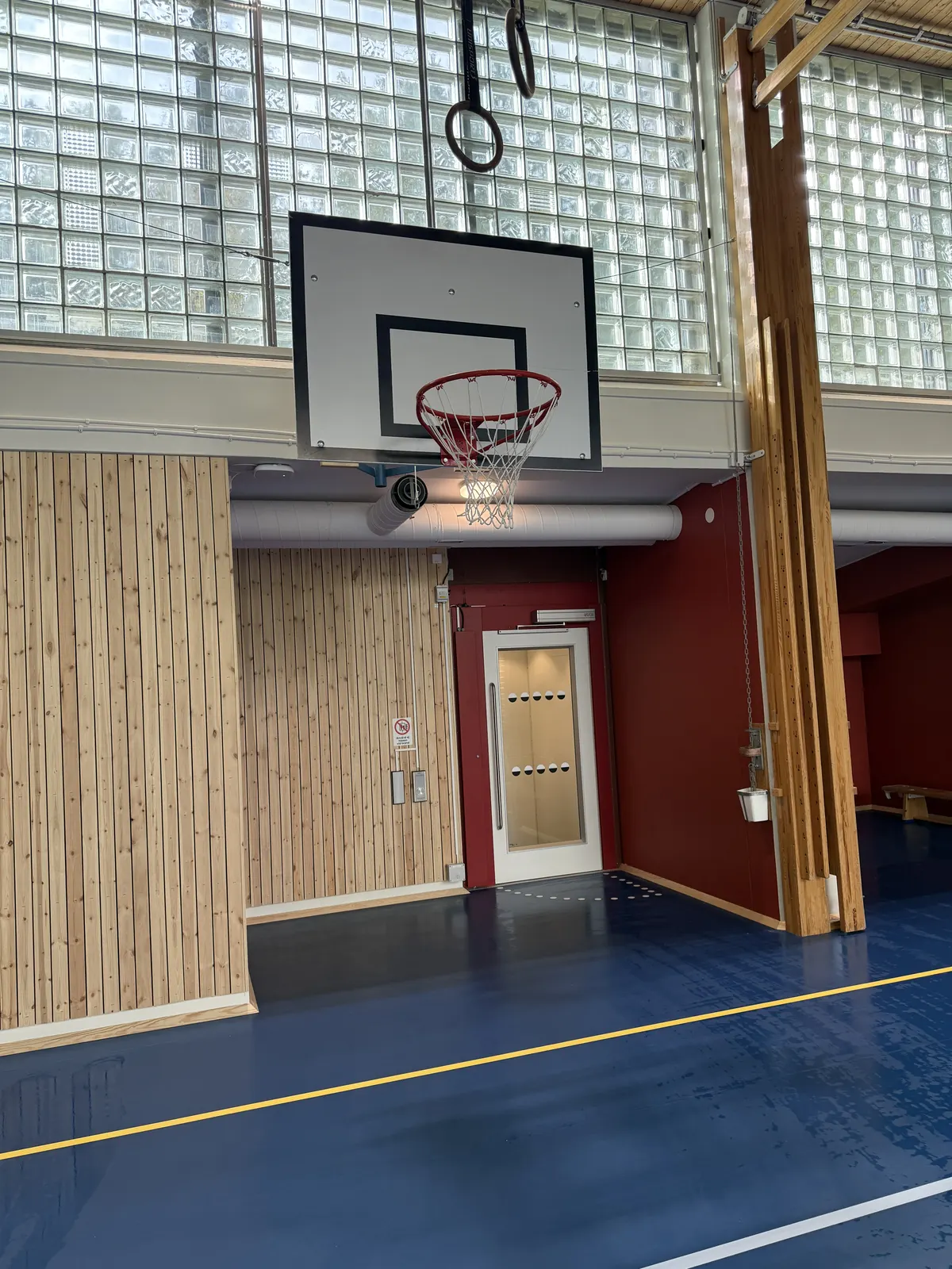 Basketkorg mot röd vägg och träribbad vägg i idrottshall