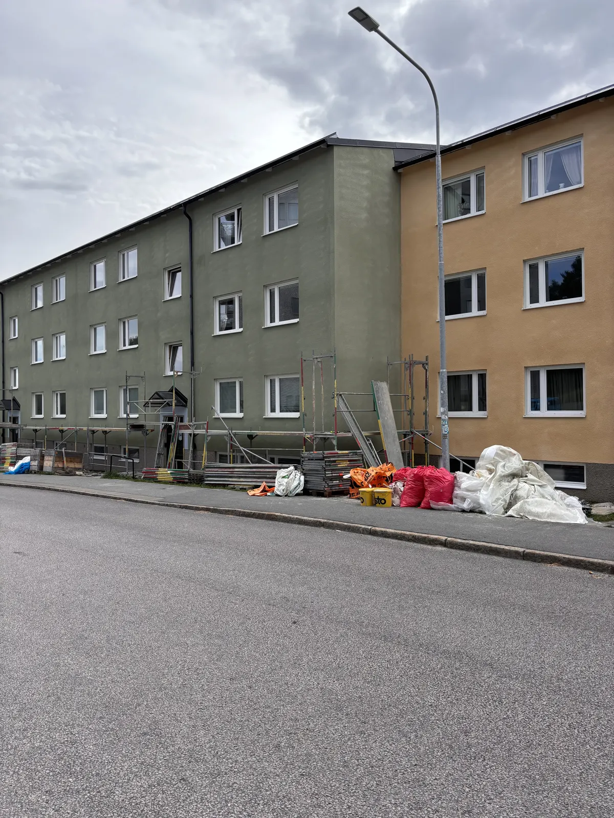 Renoverad fasad med byggmaterial uppställt längs gatan