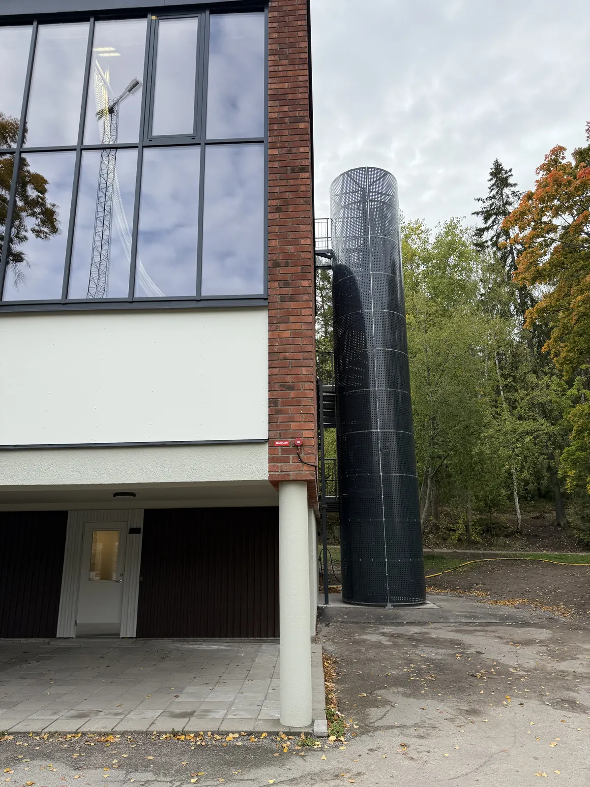 Byggnadens gavel med glasfasad och rund ventilationstrumma