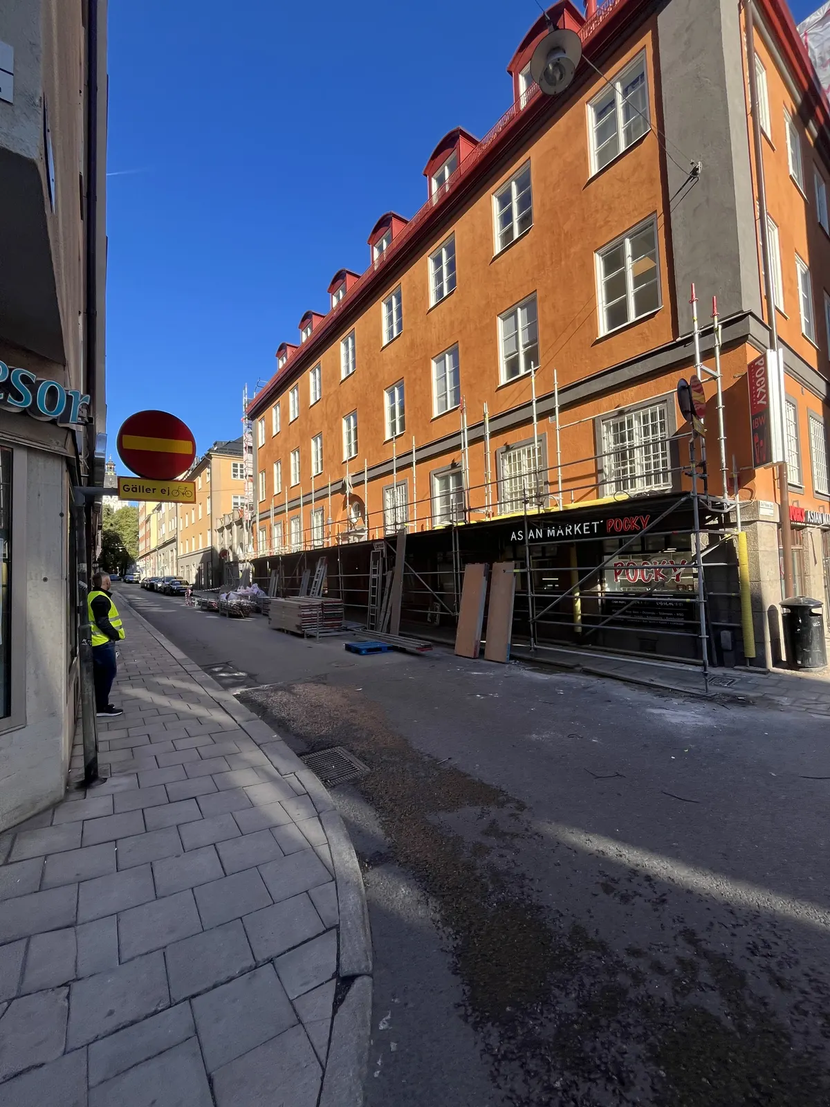 Gatuvy längs kvarteret med orange putsfasad och ställning