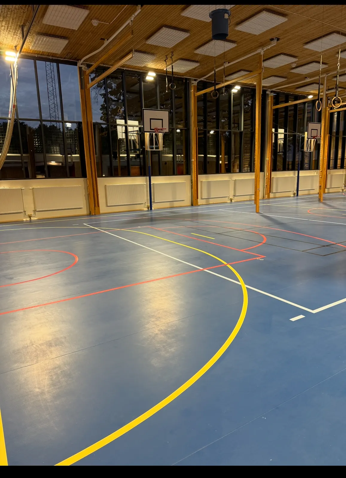 Idrottshall i kvällsljus med gula linjer på sportgolvet