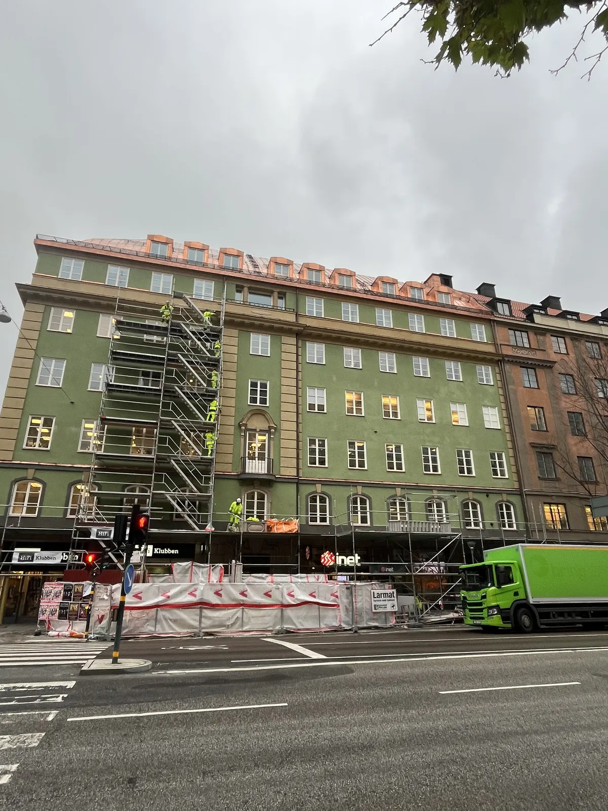 Färdig fasad sedd från gatan med lastbil och kvarvarande ställning