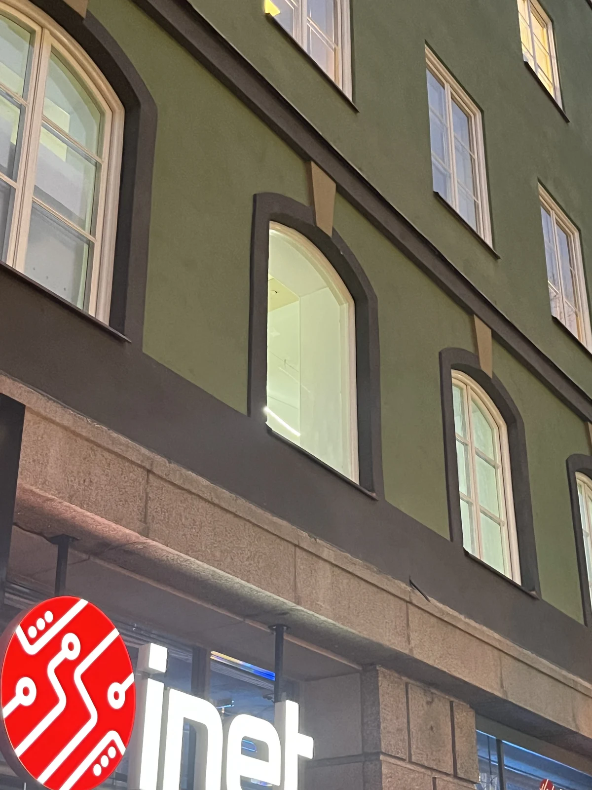 Närbild på fönsterparti och grön puts ovanför butiksentré